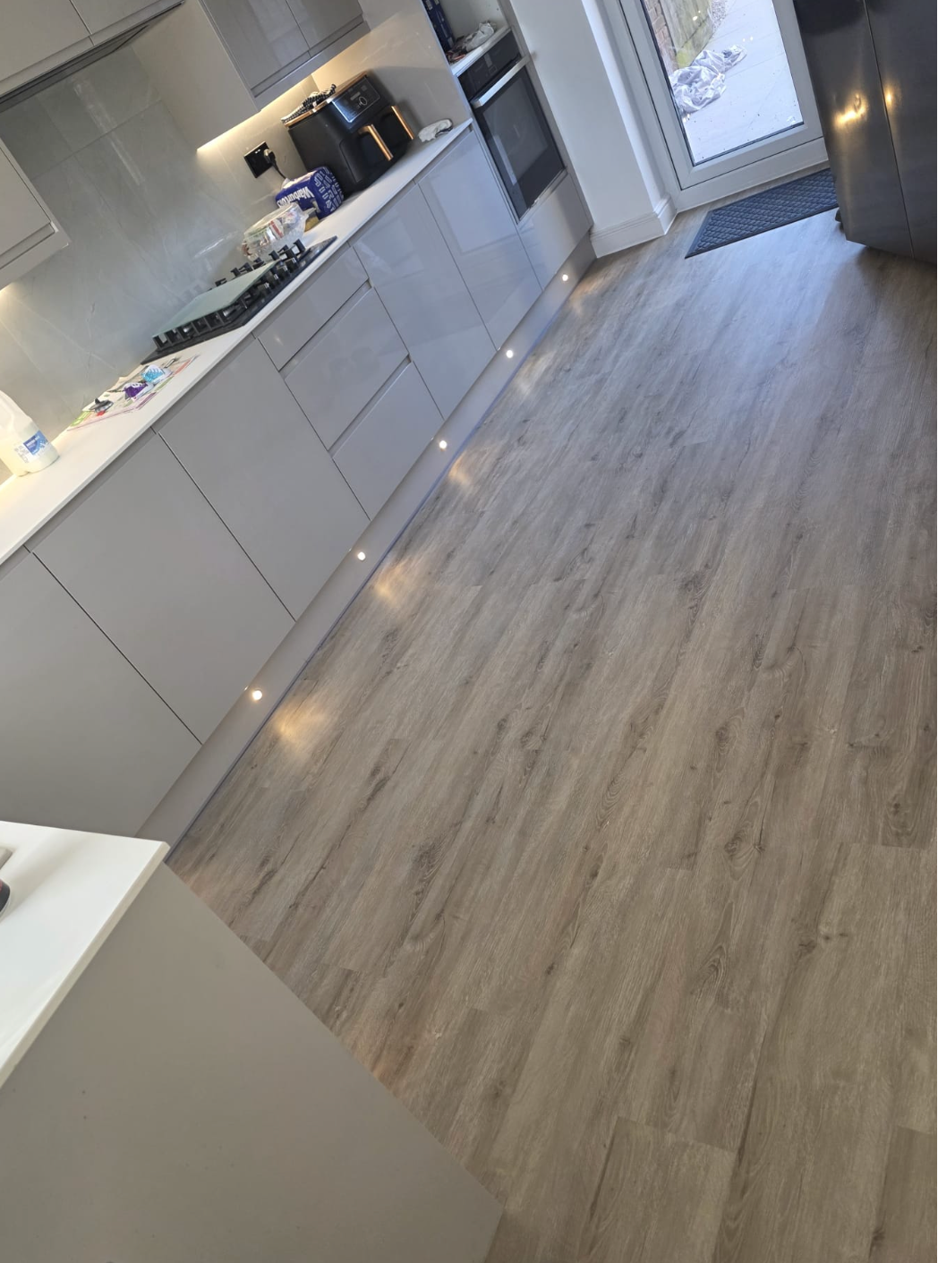 Amazon Oak SPC luxury vinyl flooring fitted in a customer kitchen, displaying realistic light oak plank flooring with waterproof, scratch-resistant and easy-maintenance properties for everyday family living.