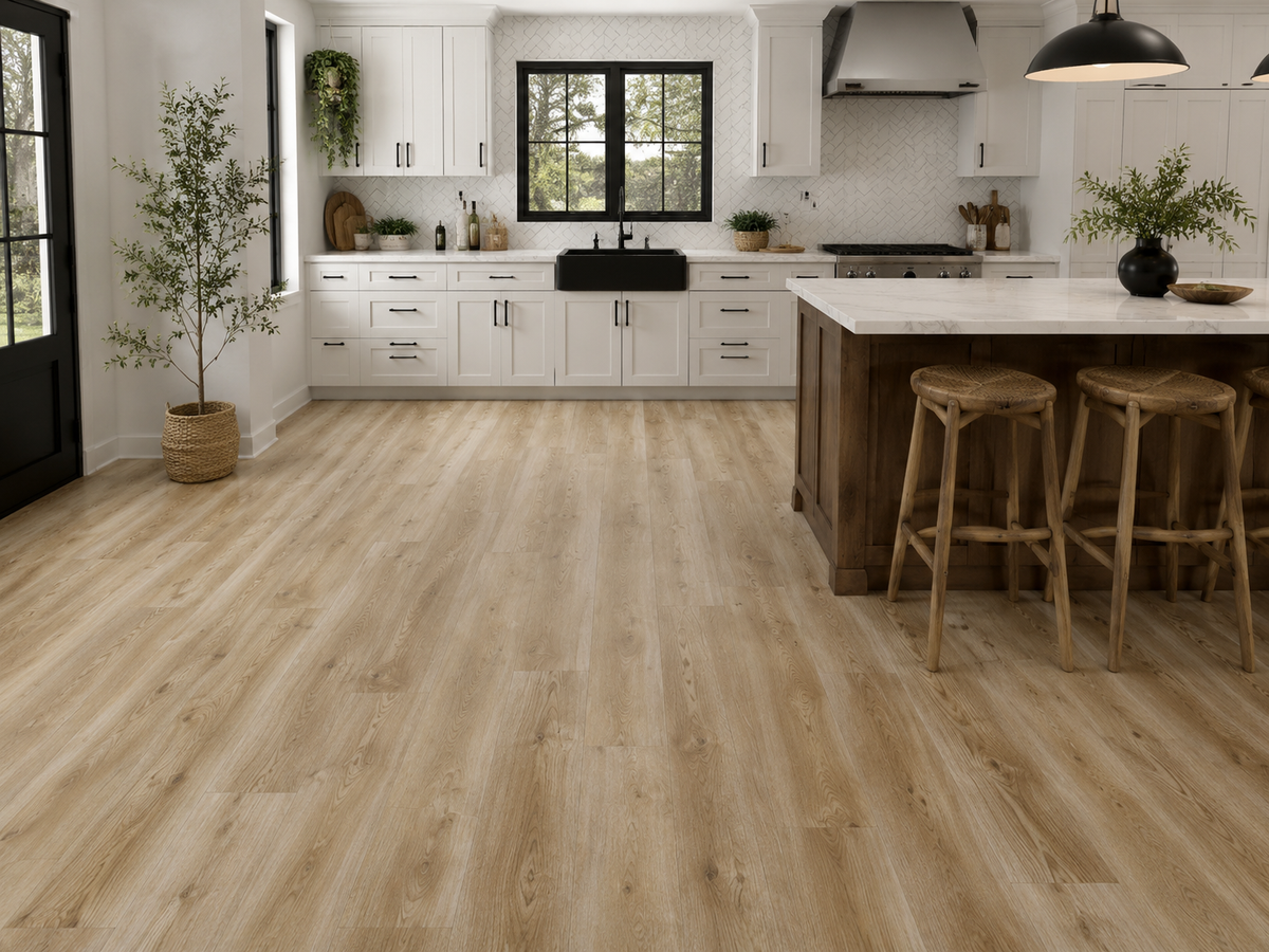 Ashdown Light Oak Luxury Click Vinyl Flooring 6mm installed in a bright contemporary kitchen, featuring wide light oak-effect planks with warm natural tones, authentic wood grain detailing, subtle knot patterns and a realistic embossed matt finish, paired with white shaker cabinets, a farmhouse sink and a large kitchen island.