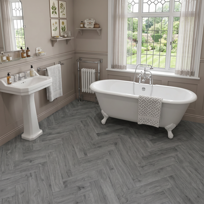 Azure Grey Herringbone Luxury Click Vinyl Flooring 5mm installed in a traditional bathroom, featuring elegant cool grey wood-effect herringbone SPC flooring with authentic grain, realistic knot detailing and a natural matt finish, complementing a freestanding bath and classic interior design.