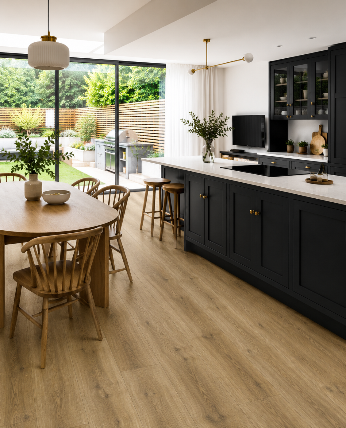 Fellside Oak XL luxury click vinyl flooring in a modern open-plan kitchen with navy shaker cabinets, oak dining furniture and large patio doors, showcasing warm natural oak tones, realistic wood grain and extra-long wide plank design.