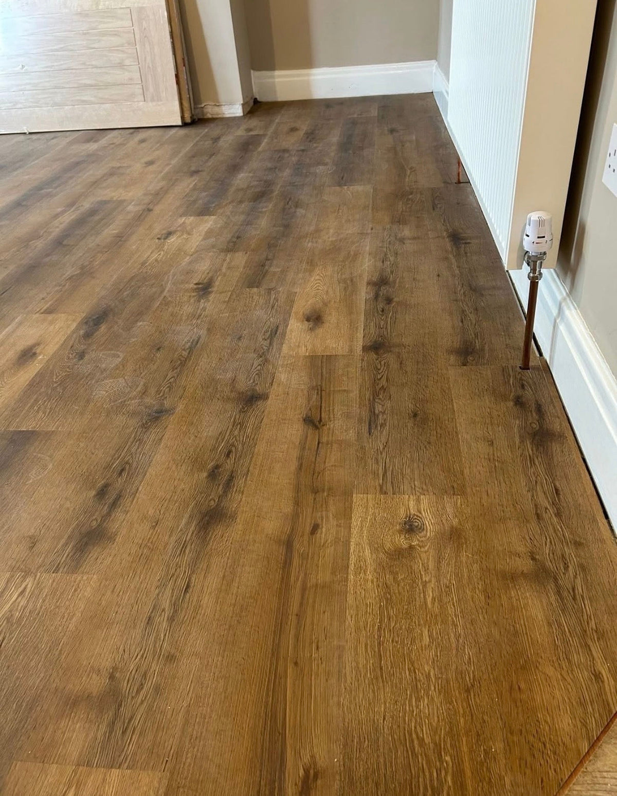 Brown wood-look laminate or vinyl plank flooring installed in a room, showing the grain and texture of the planks.