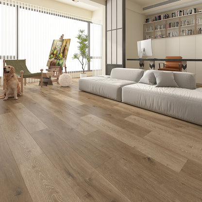 Modern open-plan living space with warm natural oak luxury vinyl plank flooring, featuring wide wood-effect boards with realistic grain and knot detailing. The bright, contemporary interior includes a low white sofa, home office, floor-to-ceiling windows, shelving, an artist's easel, indoor plant and a dog, showcasing the flooring's natural warmth and seamless finish.